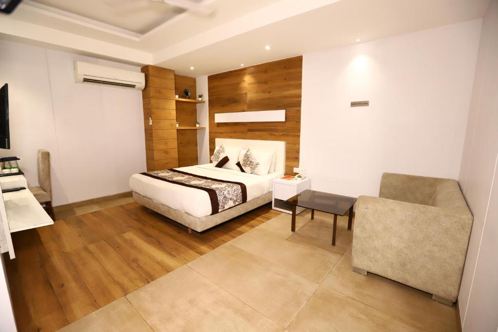 a bedroom with a bed and a chair at Hotel Kelvish by Foxi Group in New Delhi