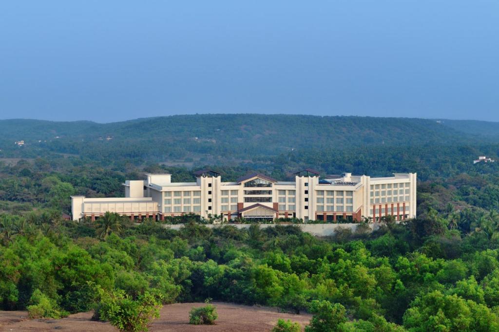 duży biały budynek w środku drzew w obiekcie The Westin Goa, Anjuna w mieście Anjuna