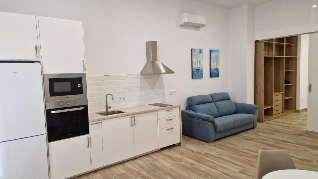 uma cozinha com armários brancos e uma cadeira azul em Carmela estudio em Málaga
