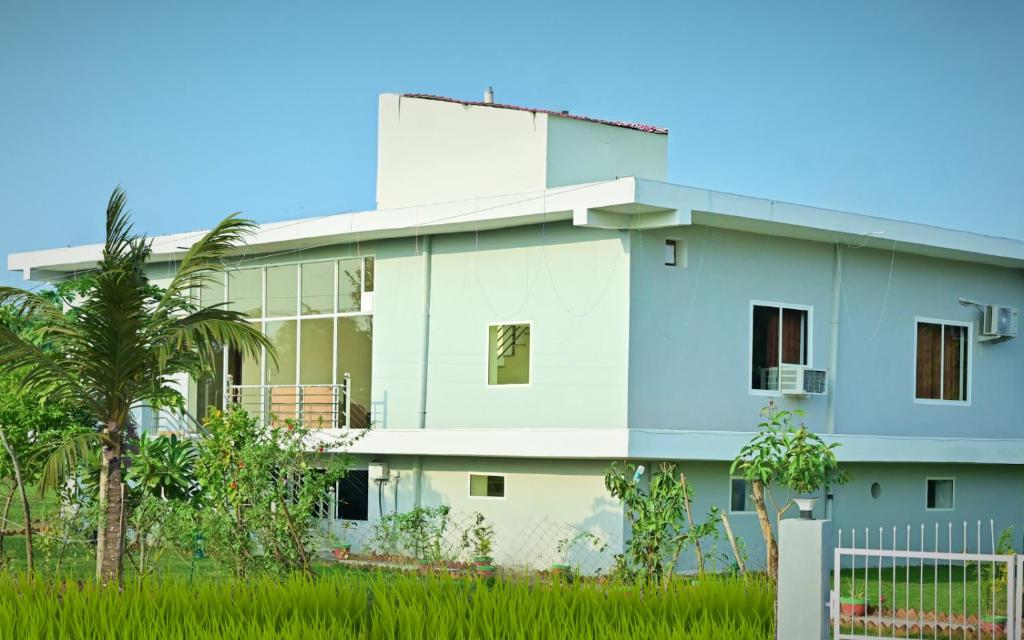 un edificio blanco con una palmera delante en Ranthambhore Nature Farm, en Sawāi Mādhopur