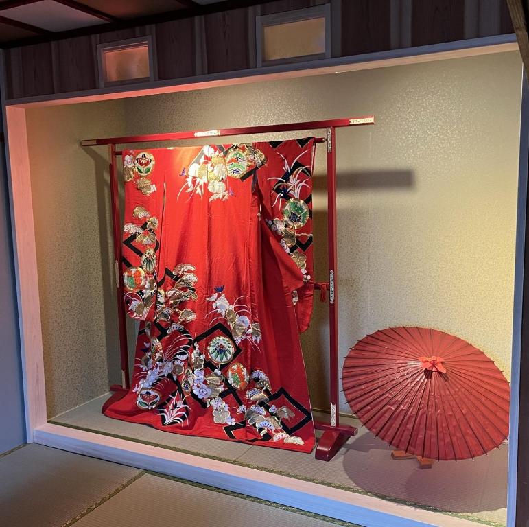 uma janela com um vestido vermelho e um guarda-chuva em Maika - renting a whole house 1日1組限定の一棟貸しの宿 em Quioto