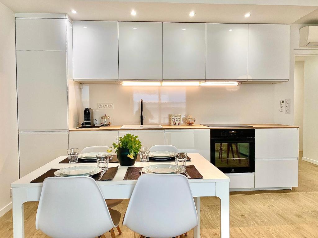 une cuisine blanche avec une table et des chaises blanches dans l'établissement Appartement Cannes 2 chambres - 14J, à Cannes