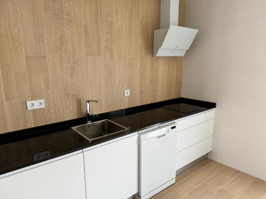 a kitchen with white cabinets and a sink at Alojamientos Robustiana in Santander