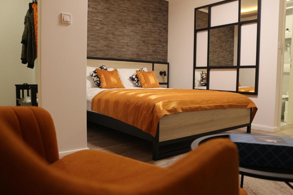 a bedroom with a bed with orange sheets and a chair at Harmony - Apartmani Tuzla in Tuzla