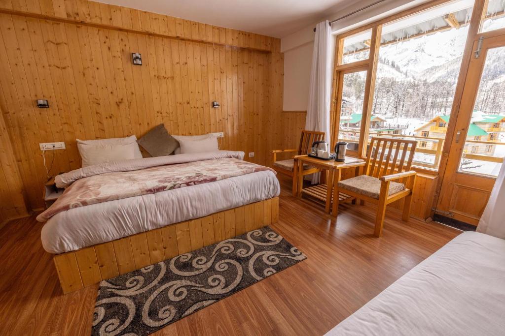 um quarto com 2 camas e uma mesa com uma cadeira em Adventure Valley em Manali