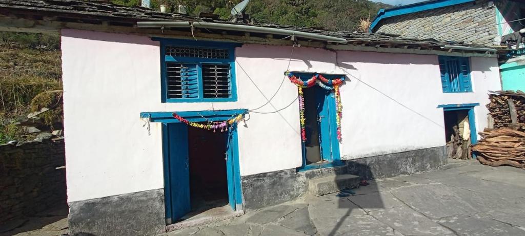 un edificio blanco y azul con ventanas y puertas azules en Harish Homestay, en Kapkot