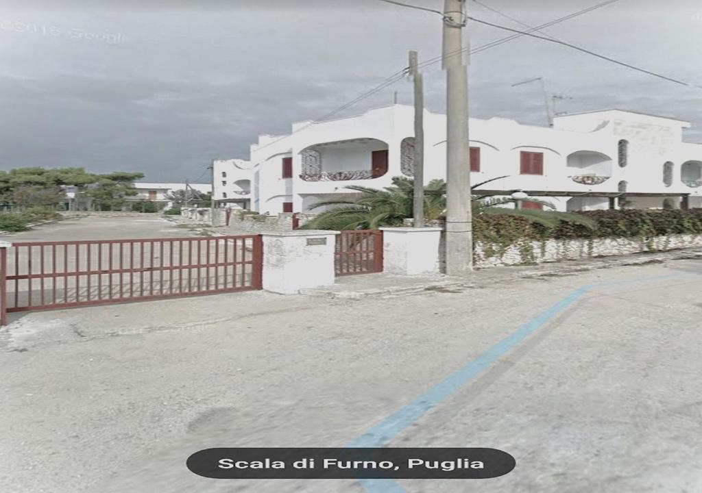 eine leere Straße mit einem Zaun und weißen Gebäuden in der Unterkunft trilocale chianca by salentolimit in Porto Cesareo