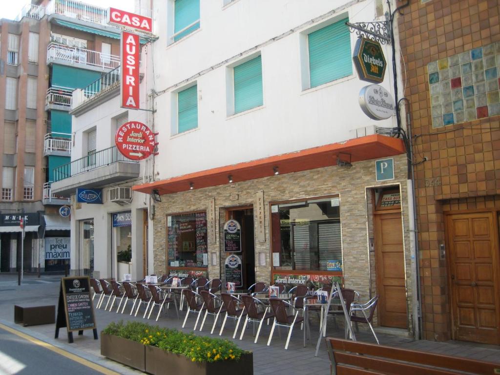a building with tables and chairs on a street at Pension Casa Austria in Calella