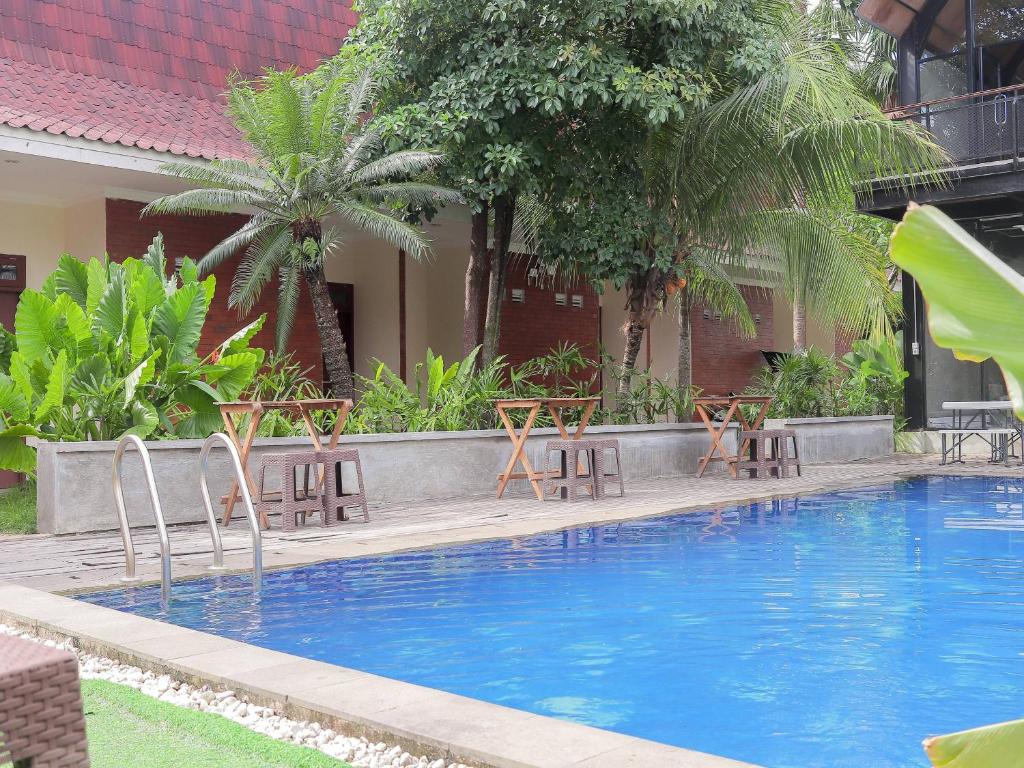 Soka Guesthouse Syariah في Martapura: مسبح وكراسي بجانب مبنى