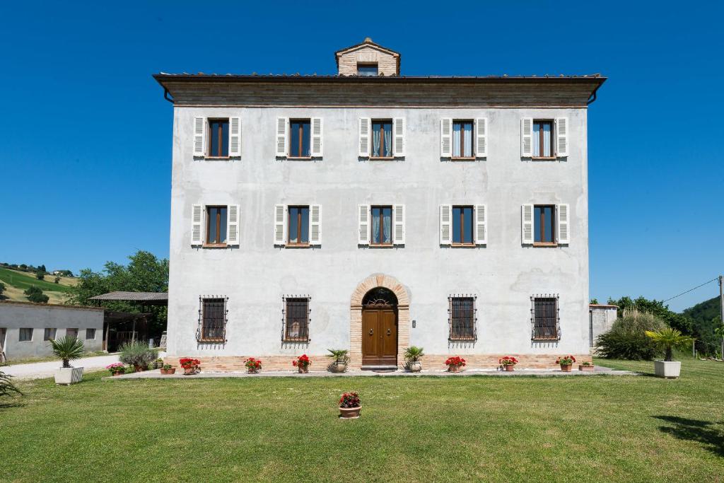 un grand bâtiment blanc avec une grande cour dans l'établissement B&B Antica Fonte del Latte, à Santa Vittoria in Matenano