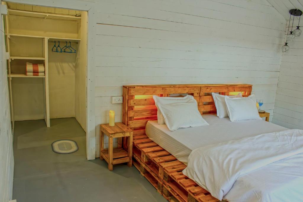 a bedroom with a wooden bed with white pillows at The Pearl Beach Resort in Canacona