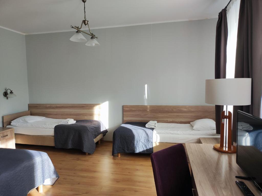 a room with two beds and a table with a lamp at Polonia in Międzyzdroje