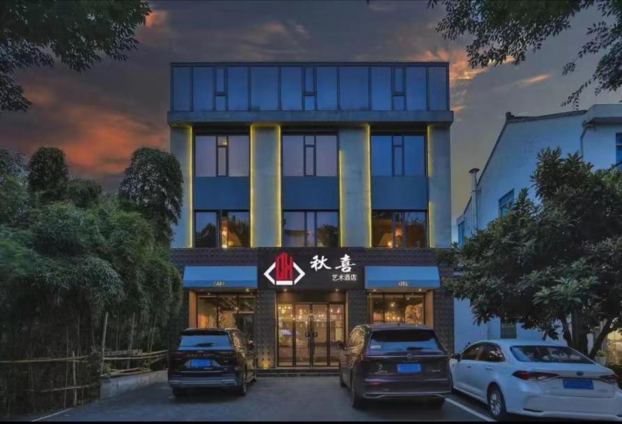 a building with two cars parked in front of it at Wuzhen Qiuxi Art Hotel in Tongxiang