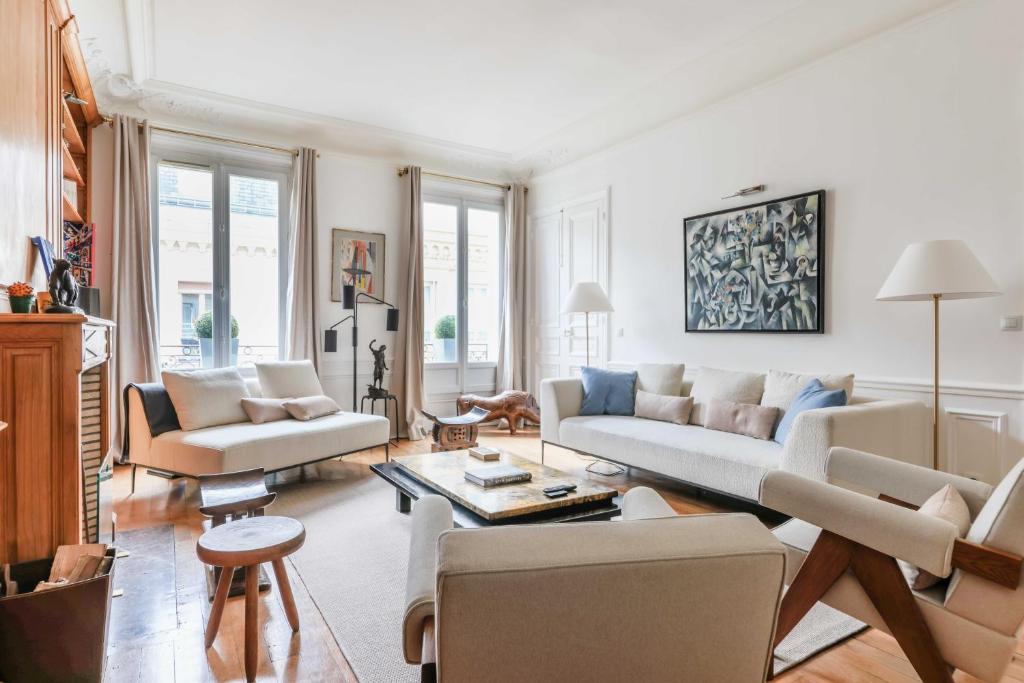 a living room with white furniture and windows at Luxury apartment for 6 people - Parc Monceau in Paris