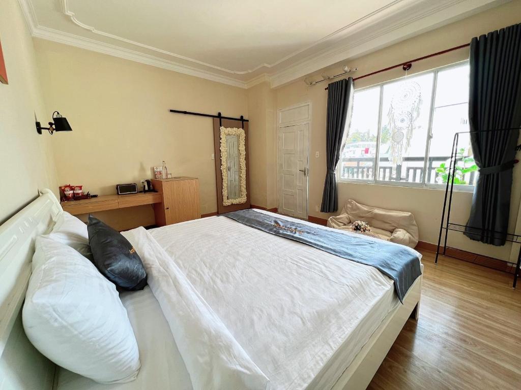 een groot wit bed in een kamer met een raam bij AroRy Hotel in Da Lat