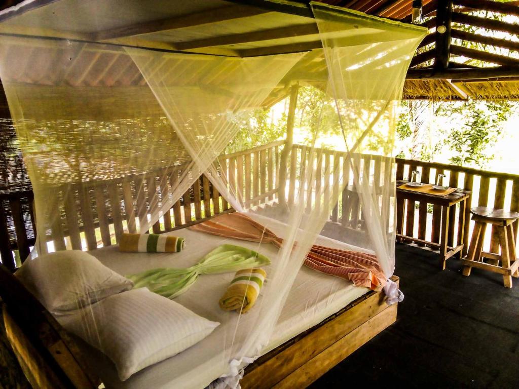 a bed on a porch with a net at Habarana Eco Lodge & Safari in Habarana