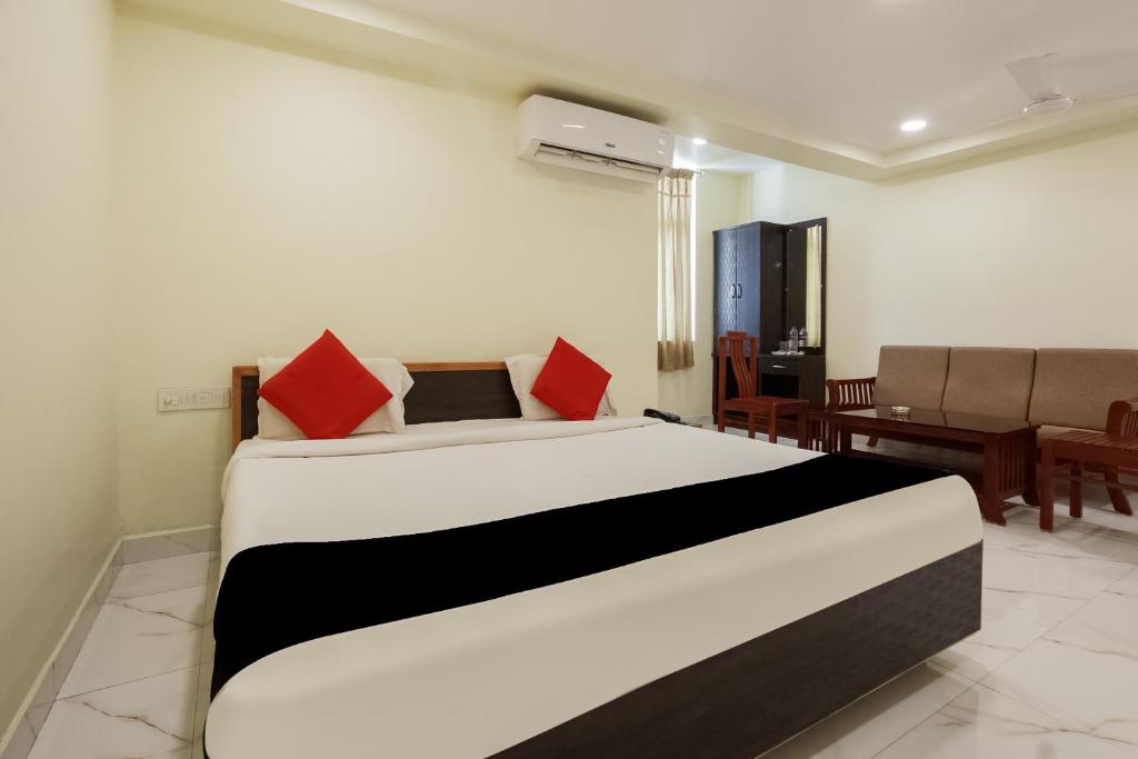 a bedroom with a large white bed with red pillows at Super Collection O 66492 Hotel Amaran in Tallākulam