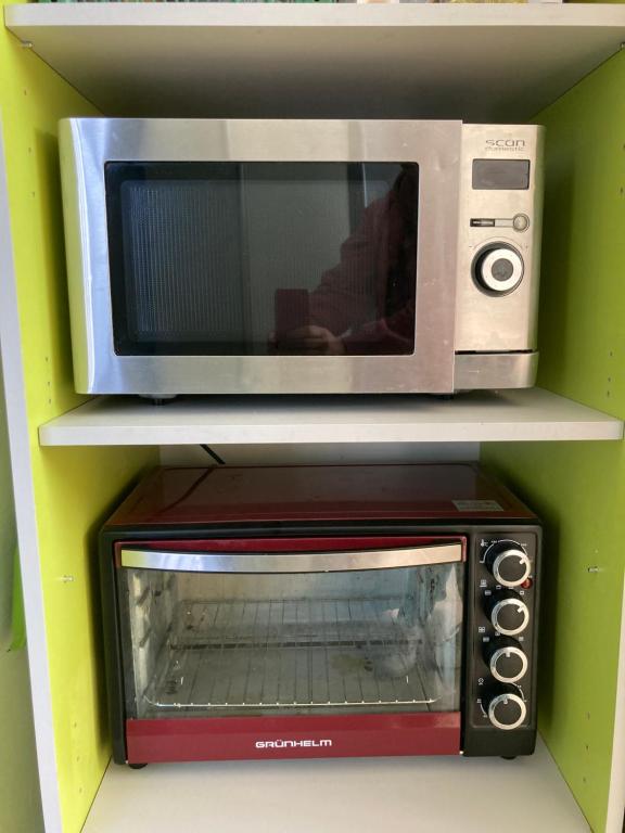 un four micro-ondes installé au-dessus d'une étagère dans l'établissement Green Kitchen Apartments, à Moukatcheve