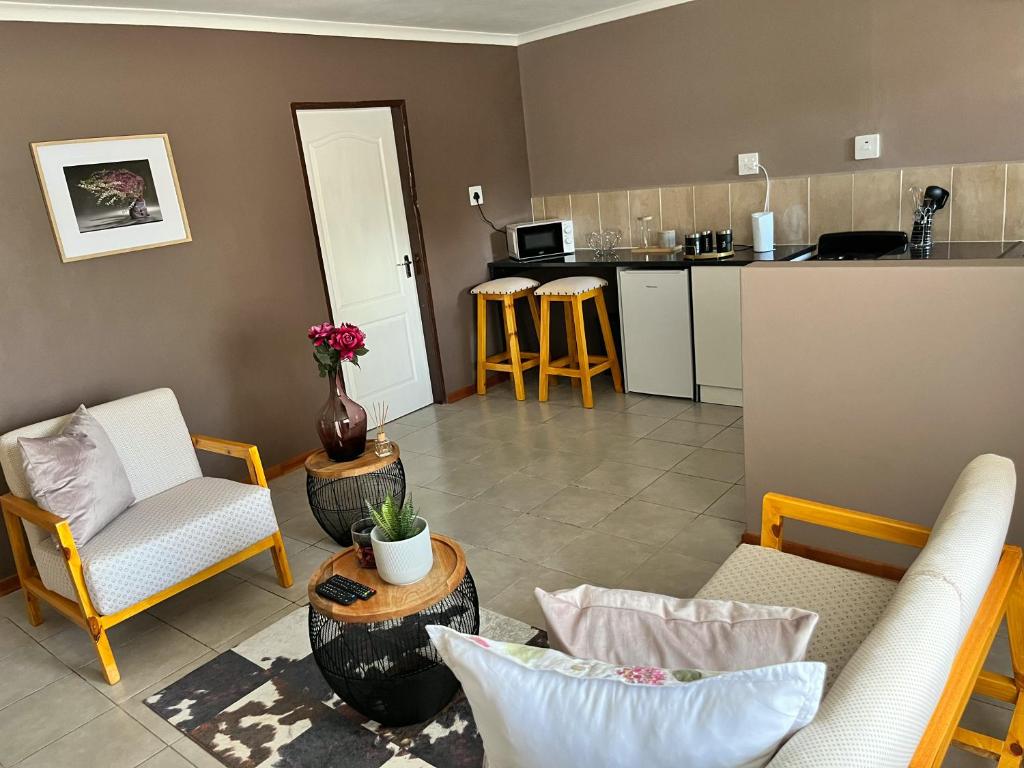 ein Wohnzimmer mit einem Sofa und Stühlen sowie eine Küche in der Unterkunft Mapalesa Guest House in Mohales Hoek