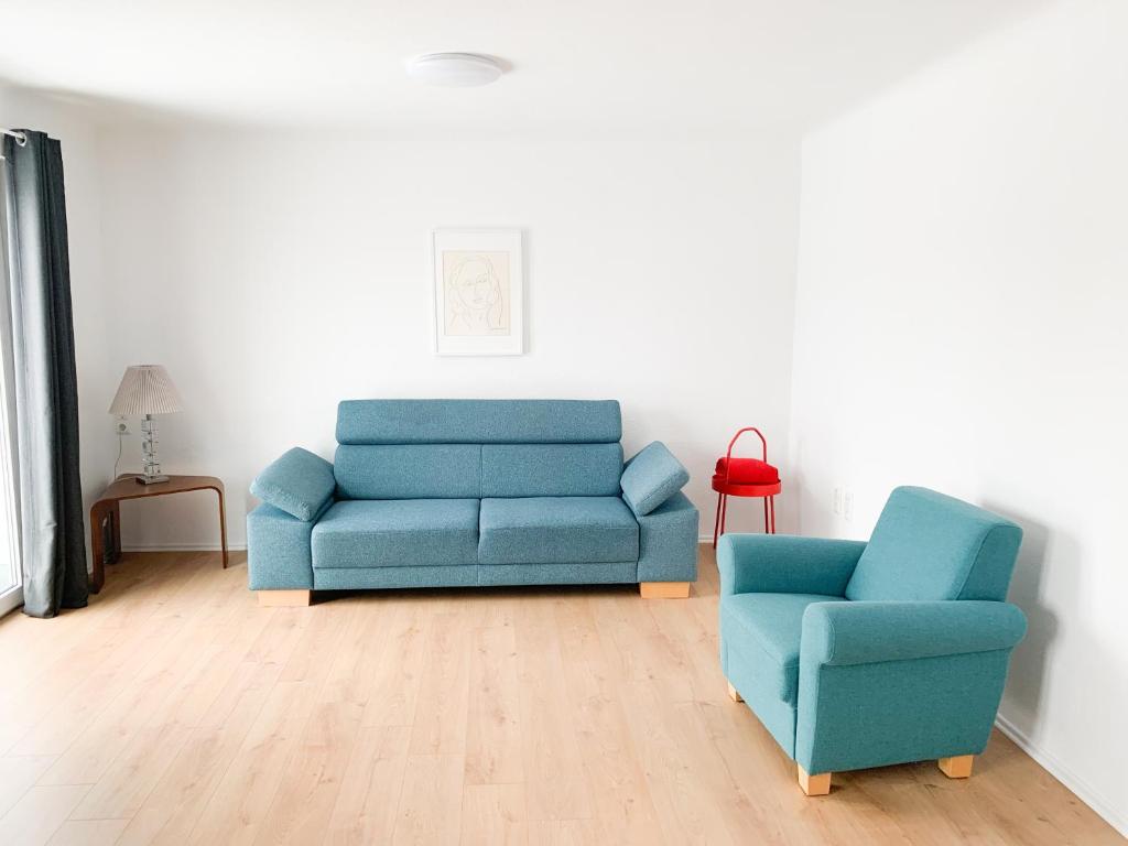 ein Wohnzimmer mit einem blauen Sofa und einem Stuhl in der Unterkunft Spacious house for large groups and families in Würzburg