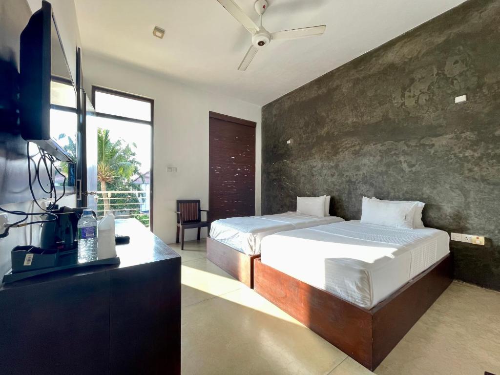 a bedroom with a bed and a desk with a television at Olanro Hotel Negombo in Negombo