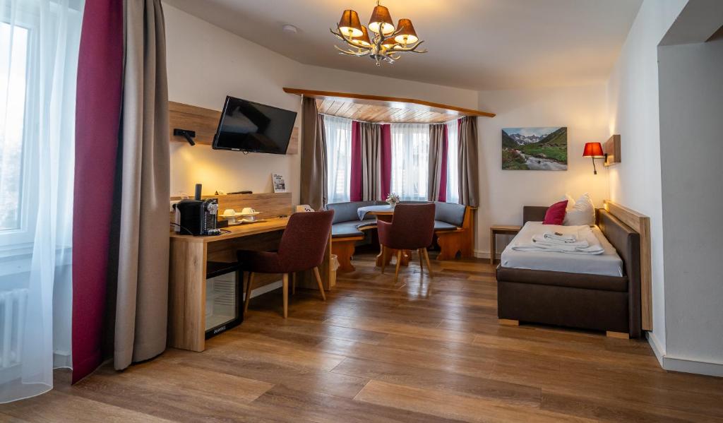 ein Hotelzimmer mit einem Schreibtisch, einem Bett und einem Tisch in der Unterkunft Hotel Weißbräu in Oberhaching
