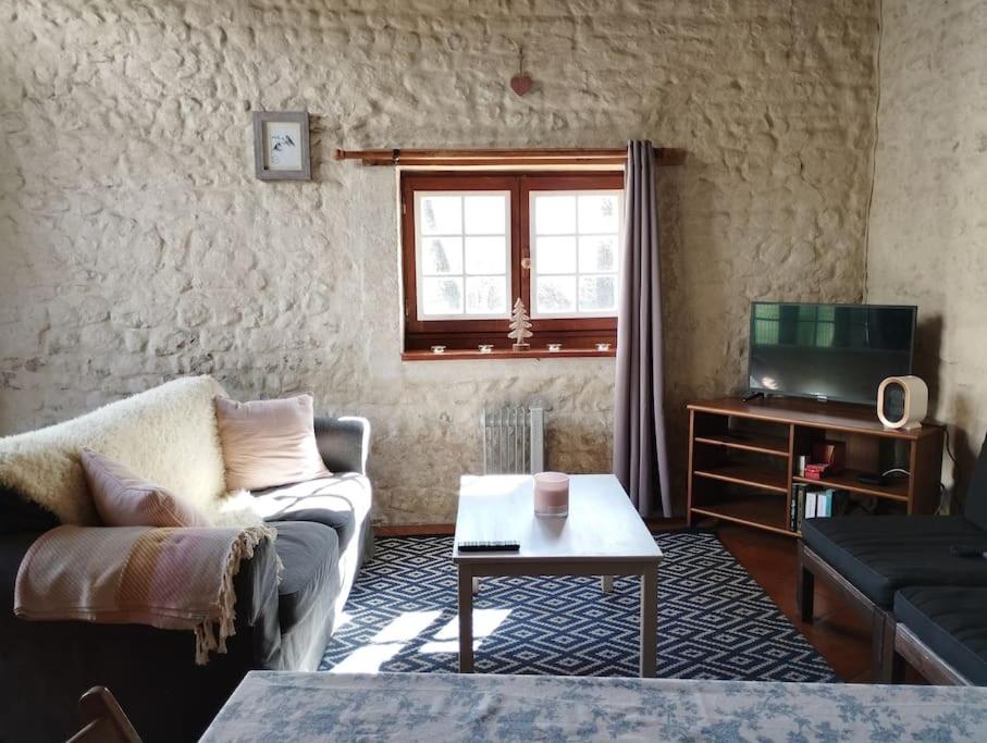 ein Wohnzimmer mit Sofa und Fernseher in der Unterkunft Cottage chaleureux au calme in Salles-de-Barbezieux