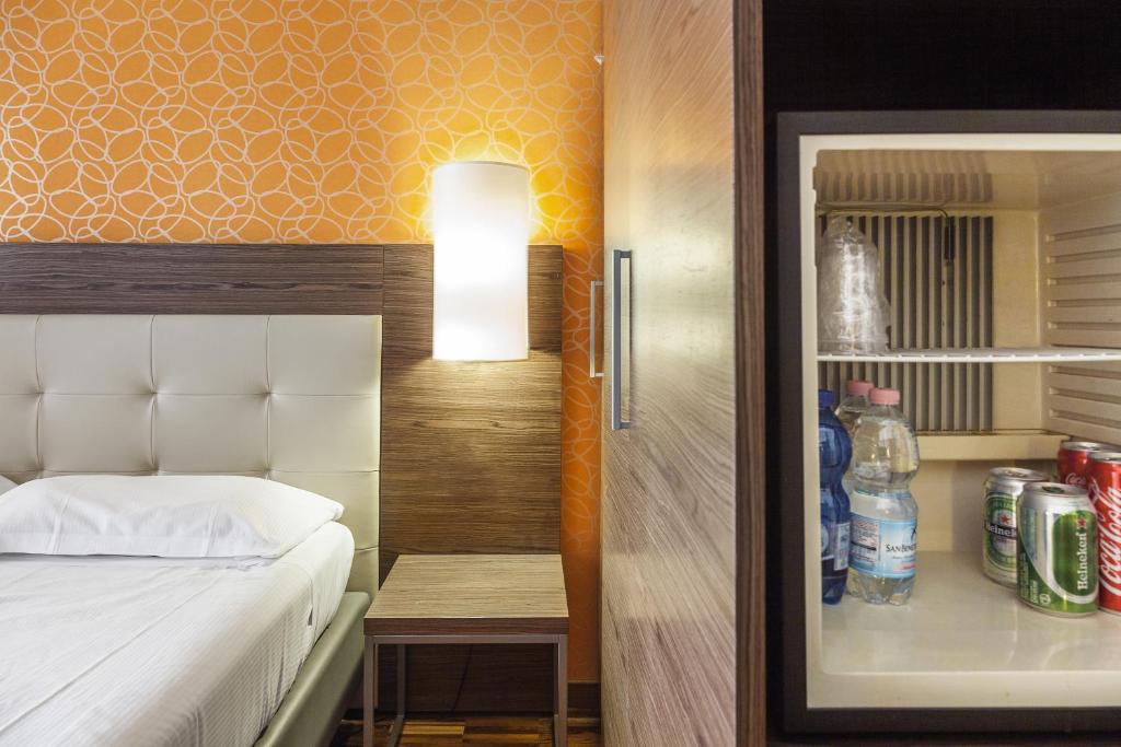 
a room with a bed and a refrigerator at Hotel Des Etrangers in Milan
