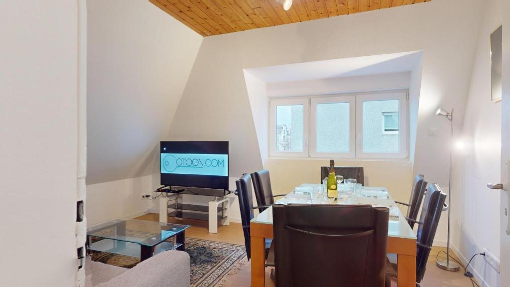 une salle à manger avec une table avec des chaises et une télévision dans l'établissement Les appartements de Georges avec parking, à Colmar