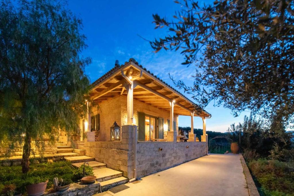 a house with a wooden roof with a pathway at Villa Vitsilias under the cretan sky in Aïtánia