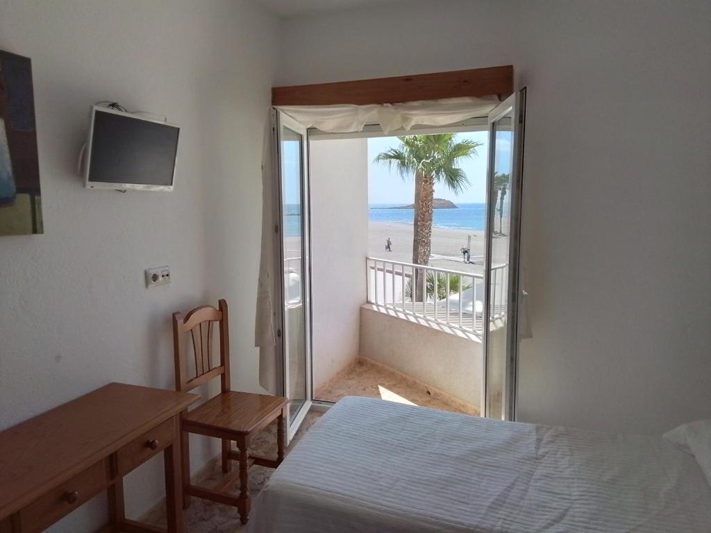 a bedroom with a bed and a view of the beach at Pensión sol y playa in Carboneras