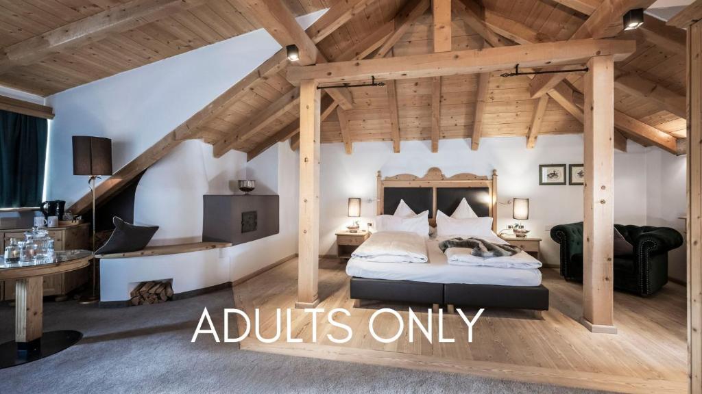 ein Schlafzimmer mit einem Bett in einem Zimmer mit Holzdecken in der Unterkunft Hotel Acadia - Adults Mountain Home in Wolkenstein in Gröden