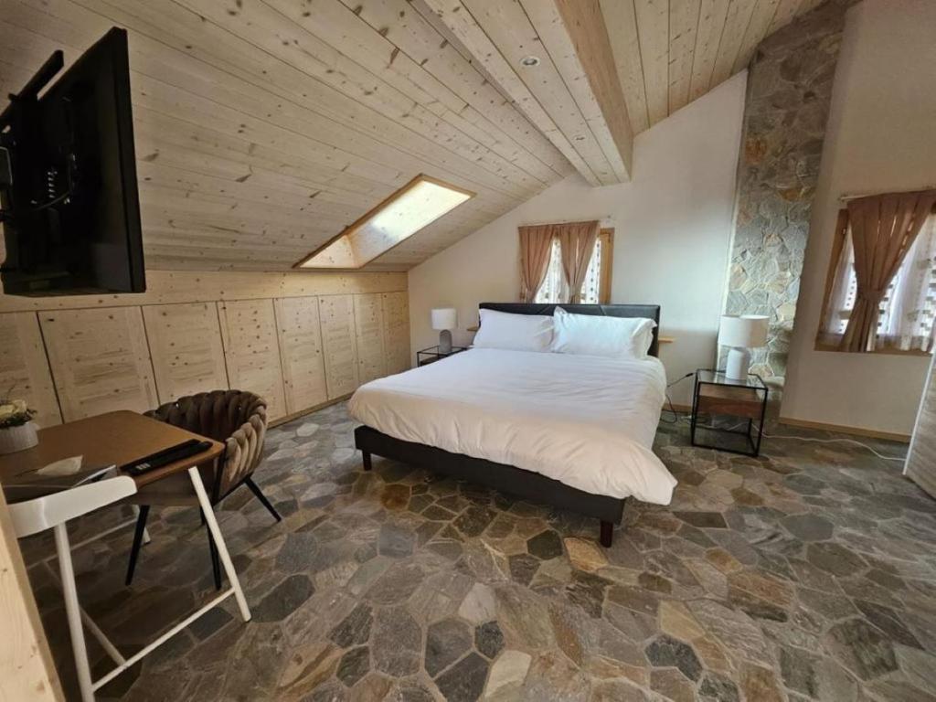 a bedroom with a bed and a desk and a television at Chalet Familial Sublime in Crans-Montana