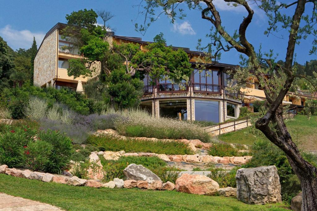 une maison sur une colline avec un jardin dans l'établissement Poiano Garda Resort Hotel, à Garde