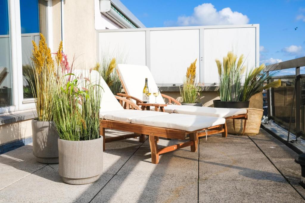 une terrasse avec 2 chaises, une table et des plantes en pot dans l'établissement holiday vibes! penthouse-studio near beach, à Ostende