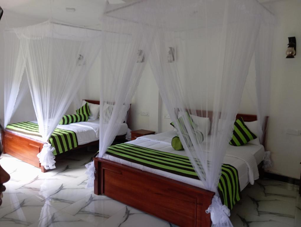 2 łóżka w pokoju z zieloną i białą pościelą w obiekcie Forest Paddy Homestay w mieście Ella