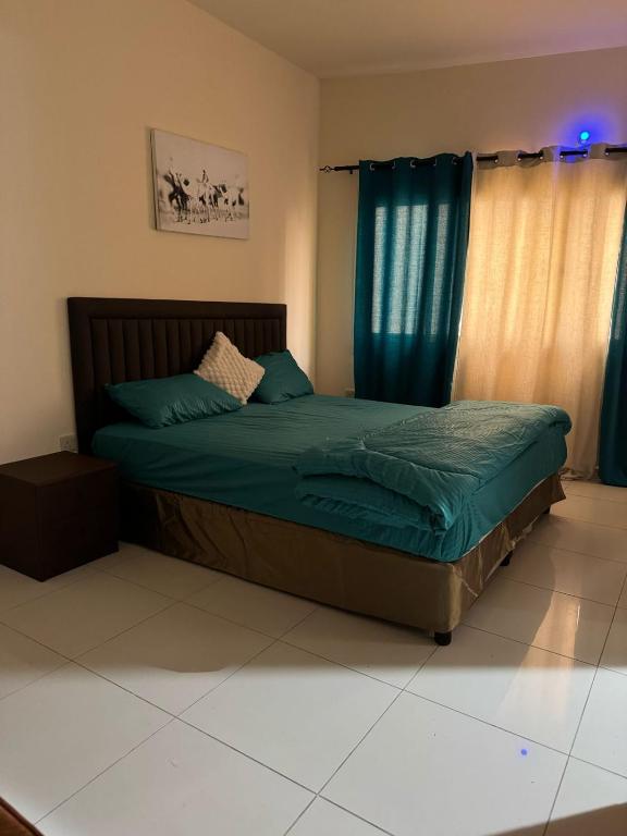 a bedroom with a bed with blue sheets and blue curtains at Fully Furnished Studio Appartment next to Sharaf DG metro Station in Dubai