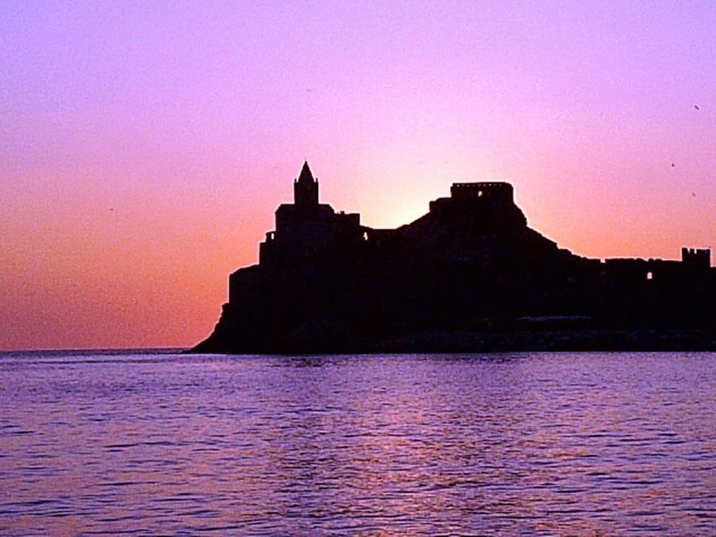 uma silhueta de uma ilha no oceano ao pôr do sol em MAGIA DI MARE em La Spezia