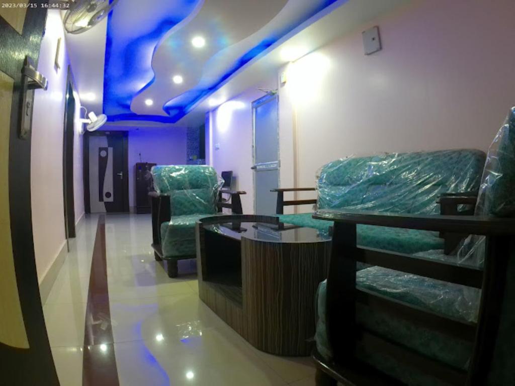 une chambre avec des chaises, une table et un plafond bleu dans l'établissement Roop Amrit Guest House , Agartala, à Agartala