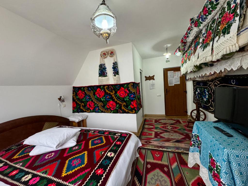 Un dormitorio con una cama con una manta de colores. en Pensiunea Irina Maramureș en Deseşti