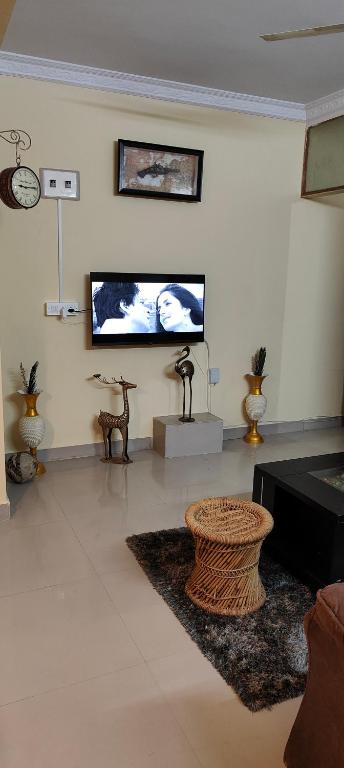 sala de estar con TV de pantalla plana en la pared en ROSHAN STAYs, en Bangalore