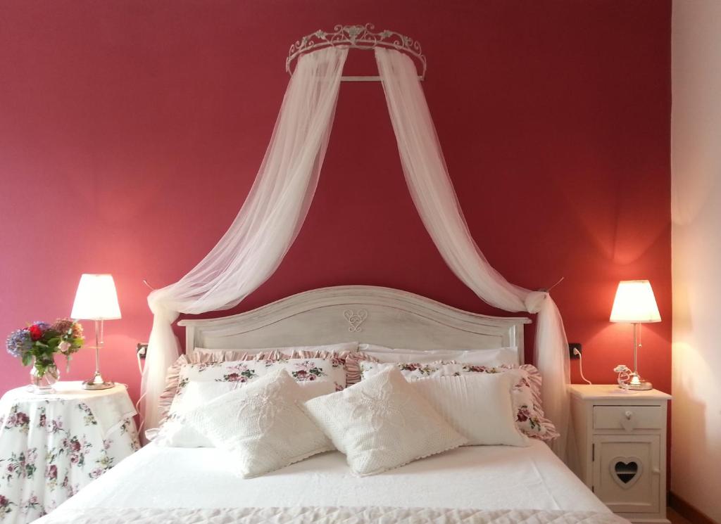 a bedroom with a white bed with a red wall at Villa San Giorgio in Pellio Superiore