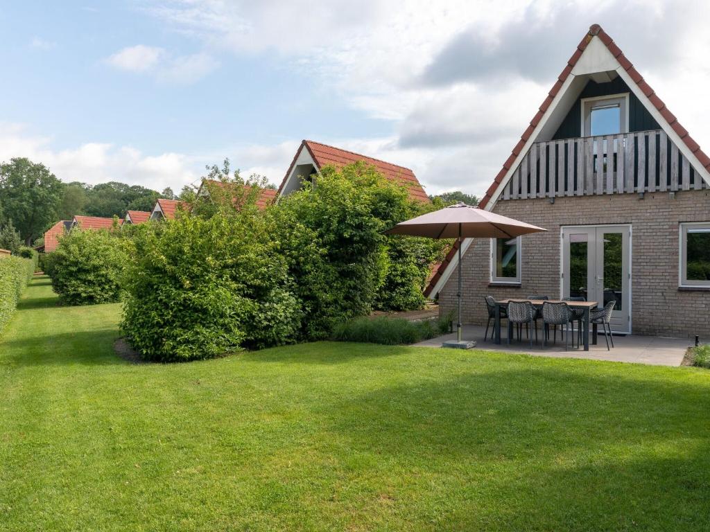 uma casa com um quintal com uma mesa e um guarda-chuva em Holiday Home with garden near Mookerplas em Plasmolen