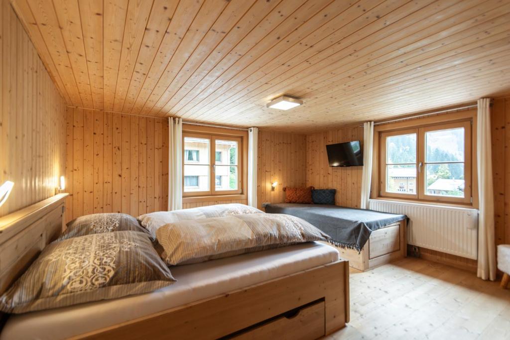 a bedroom with two beds and a tv and windows at Berghof Ferienhaus in Schröcken