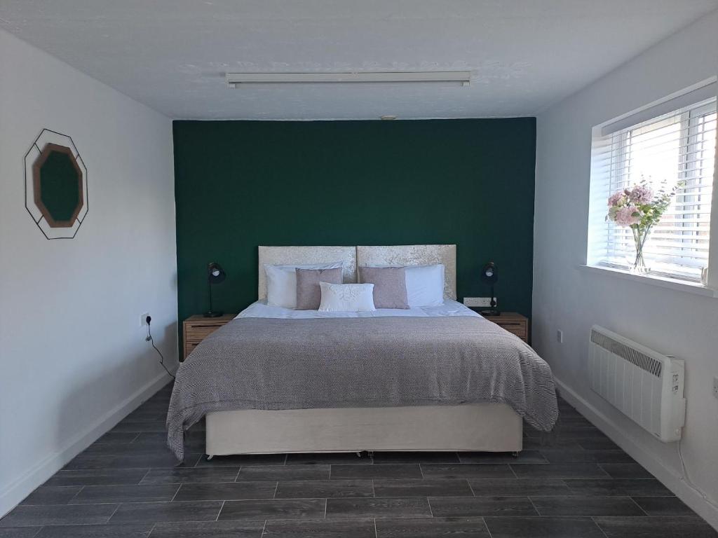 a bedroom with a large bed with a green wall at Celtic Minor Cwtch in Swansea