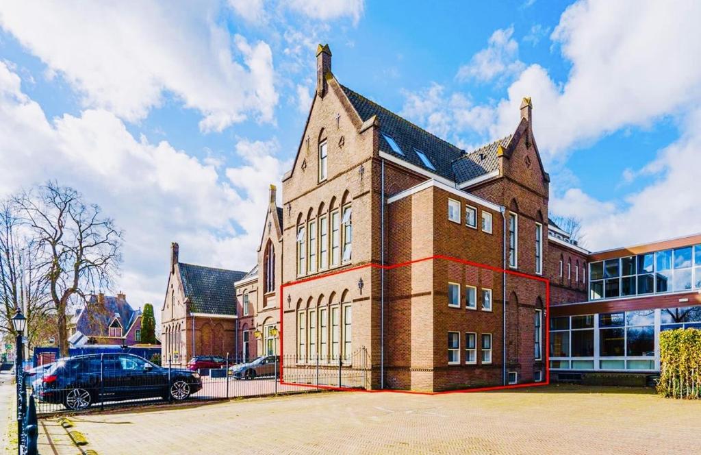 duży ceglany budynek z samochodem zaparkowanym przed nim w obiekcie Jutphaas Loft Appartement w mieście Nieuwegein