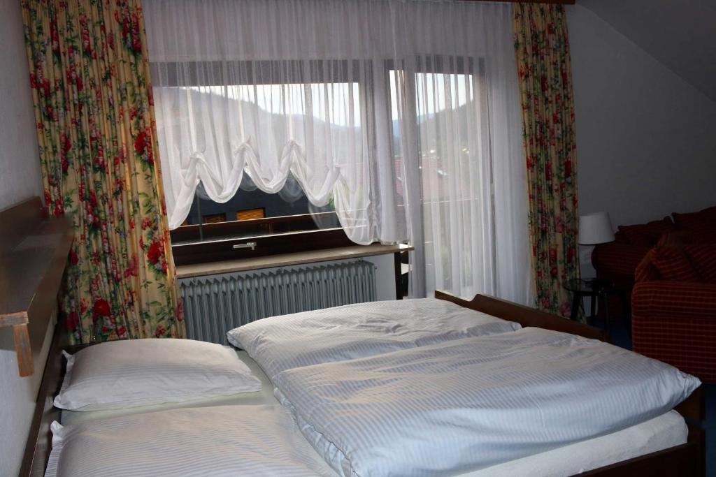a bedroom with a bed and a window with curtains at Haus am Wegle in Baiersbronn