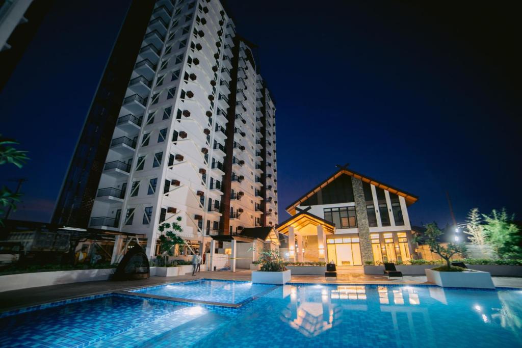 a swimming pool in front of a tall building at night at Royal Oceancrest Mactan Condominium Unit 1418 in Sudtungan