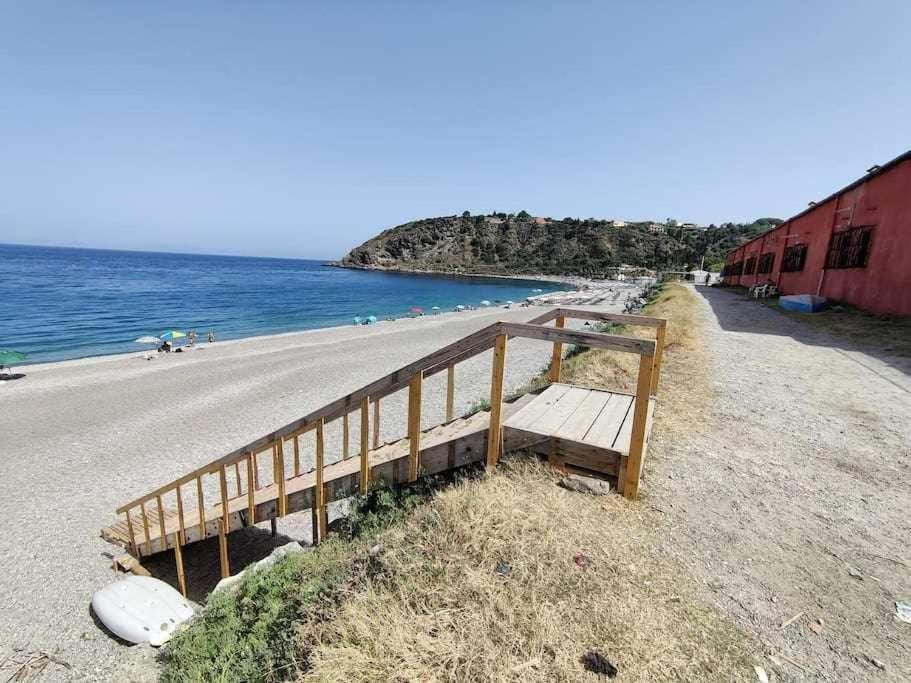 un banco de madera sentado en un lado de la playa en Cottage84 - Proppro - Milazzo, en Milazzo