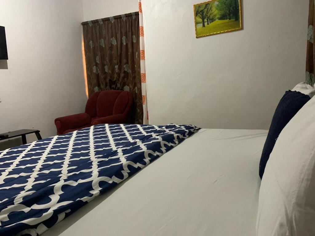 um quarto com uma cama e uma cadeira vermelha em HOMELY GUEST HOUSE em Agona